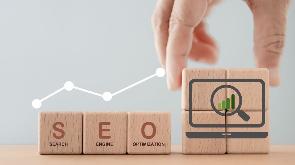 Wooden blocks spelling out 'SEO' with a hand arranging a block featuring a computer and magnifying glass icon, symbolizing search engine optimization. A line graph overlays the image, representing growth and improvement in SEO performance.